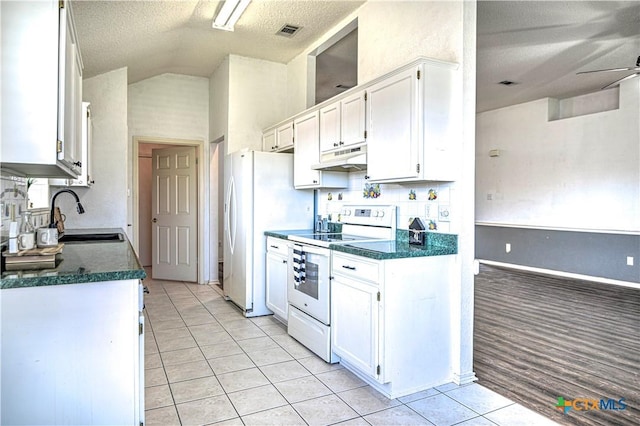 kitchen with white appliances, dark countertops, under cabinet range hood, and a sink