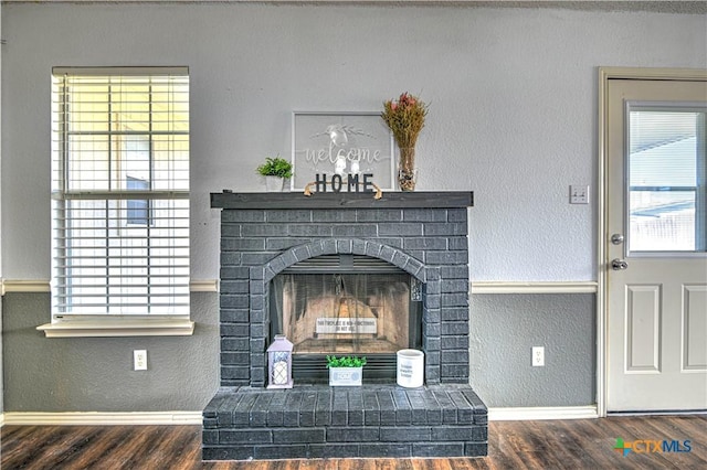 details featuring a brick fireplace, wood finished floors, baseboards, and a textured wall