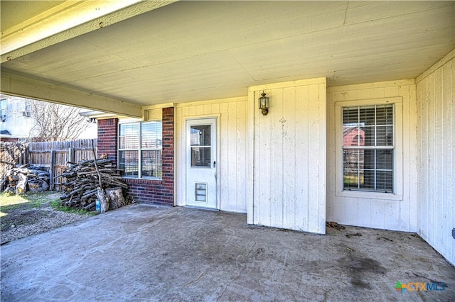 entrance to property with a patio area, brick siding, and fence