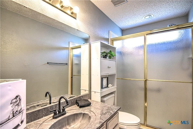 bathroom featuring visible vents, toilet, a shower with door, a textured ceiling, and a textured wall