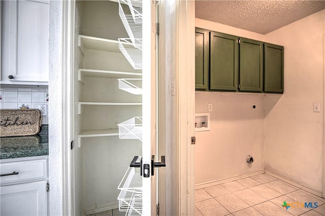 laundry room featuring hookup for a washing machine, light tile patterned floors, cabinet space, electric dryer hookup, and a textured ceiling