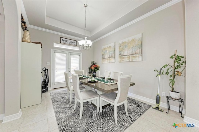 tiled dining room with a tray ceiling, an inviting chandelier, and ornamental molding