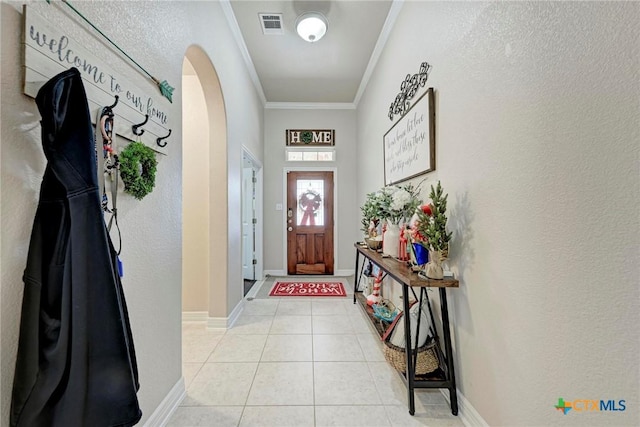 doorway to outside with ornamental molding and light tile patterned floors