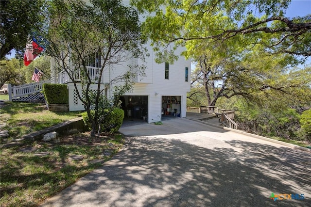 view of front of house with concrete driveway, a garage, and stairway