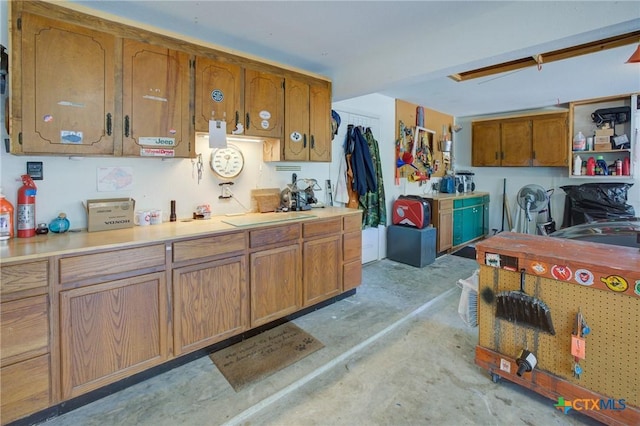 kitchen with brown cabinetry, concrete flooring, and light countertops