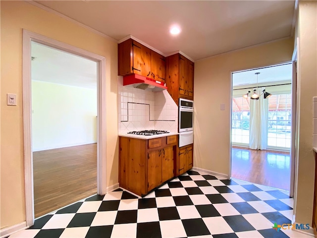 kitchen featuring stainless steel oven, an inviting chandelier, ornamental molding, backsplash, and white gas stovetop