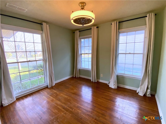 unfurnished room featuring a textured ceiling, plenty of natural light, and dark wood-type flooring