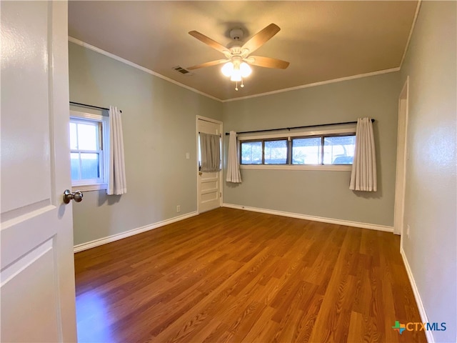 unfurnished room with ornamental molding, wood-type flooring, ceiling fan, and a wealth of natural light