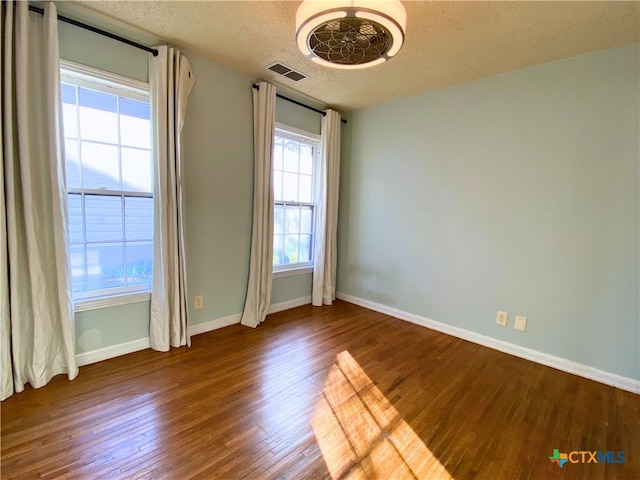 empty room featuring a textured ceiling and wood-type flooring