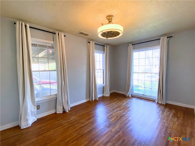 empty room featuring a textured ceiling and dark hardwood / wood-style floors