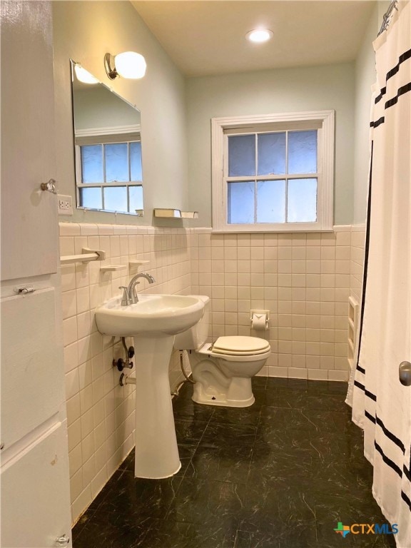 bathroom featuring tile walls and toilet