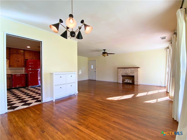 unfurnished living room featuring ceiling fan, a brick fireplace, and dark hardwood / wood-style floors