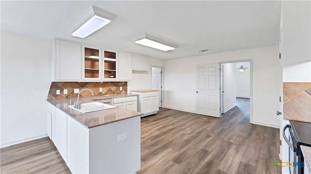 kitchen with kitchen peninsula, decorative backsplash, hardwood / wood-style floors, and white cabinets