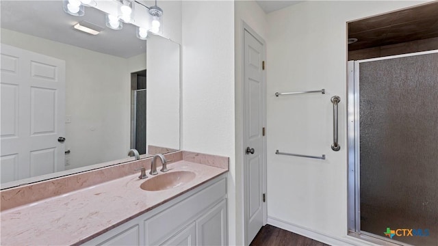 bathroom with hardwood / wood-style floors, vanity, and a shower with shower door