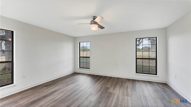 empty room with ceiling fan, a healthy amount of sunlight, and wood-type flooring