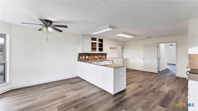 kitchen with kitchen peninsula, white cabinetry, sink, and dark hardwood / wood-style floors