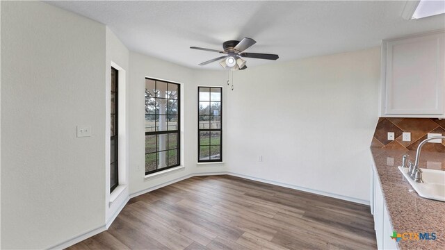 unfurnished dining area featuring light hardwood / wood-style flooring, ceiling fan, and sink