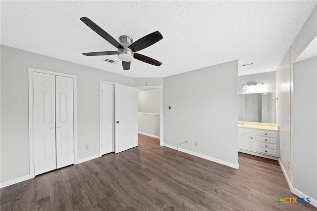 1311 Speight Ave, Waco, TX 76706 - unfurnished bedroom featuring ceiling fan, ensuite bathroom, a textured ceiling, dark hardwood / wood-style flooring, and multiple closets