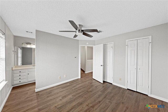 1311 Speight Ave, Waco, TX 76706 - unfurnished bedroom featuring ensuite bath, a textured ceiling, multiple closets, dark hardwood / wood-style floors, and ceiling fan