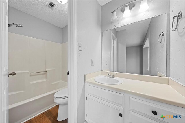 1311 Speight Ave, Waco, TX 76706 - full bathroom featuring toilet, wood-type flooring, tub / shower combination, a textured ceiling, and vanity
