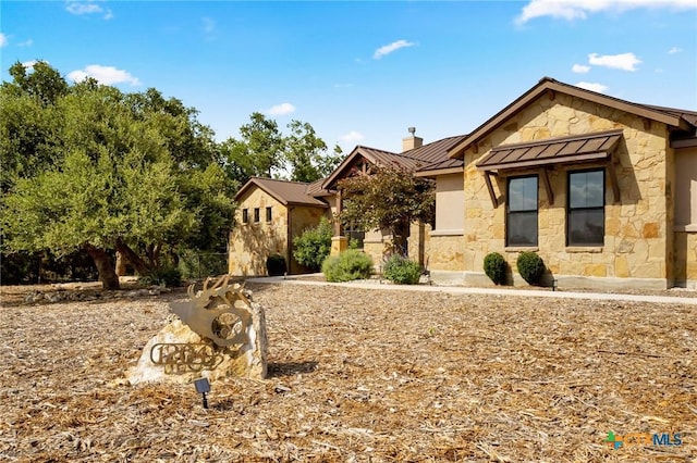 1204 Salt Lick Dr, New Braunfels, TX 78132 - view of front of home with stone siding, a standing seam roof, a chimney, and a metal roof