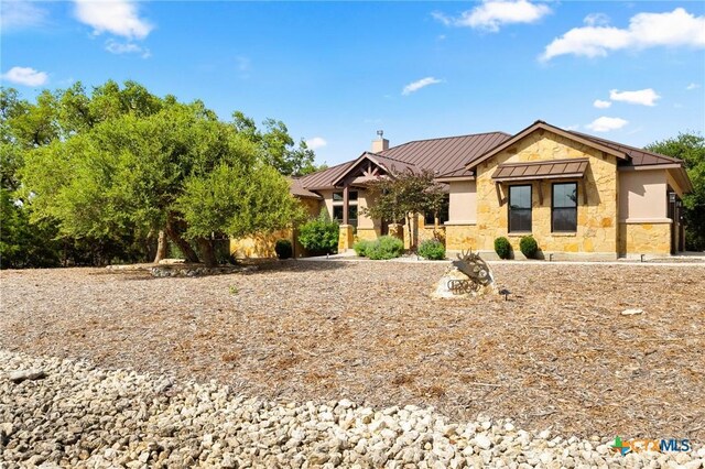 1204 Salt Lick Dr, New Braunfels, TX 78132 - view of front of house with a standing seam roof, a chimney, a metal roof, and stone siding
