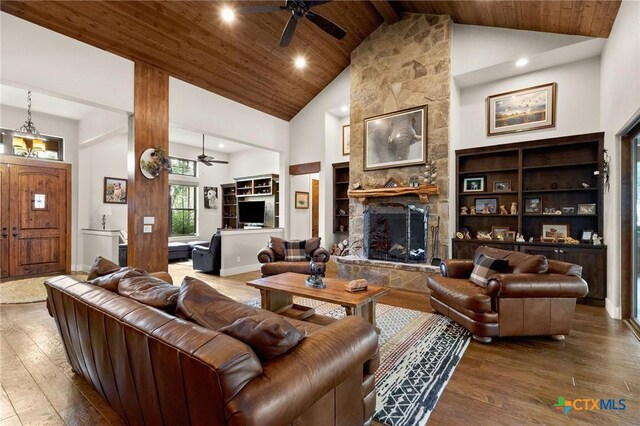 1204 Salt Lick Dr, New Braunfels, TX 78132 - living area featuring a ceiling fan, hardwood / wood-style floors, a wooden ceiling with exposed beams, high vaulted ceiling, and a stone fireplace