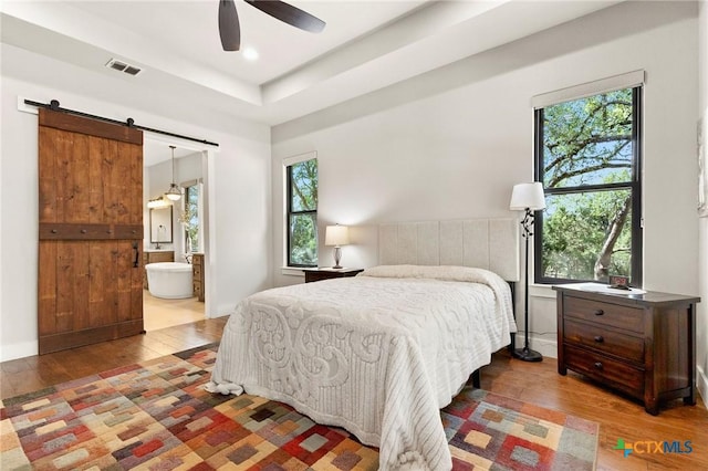 1204 Salt Lick Dr, New Braunfels, TX 78132 - bedroom with multiple windows, hardwood / wood-style flooring, and a barn door