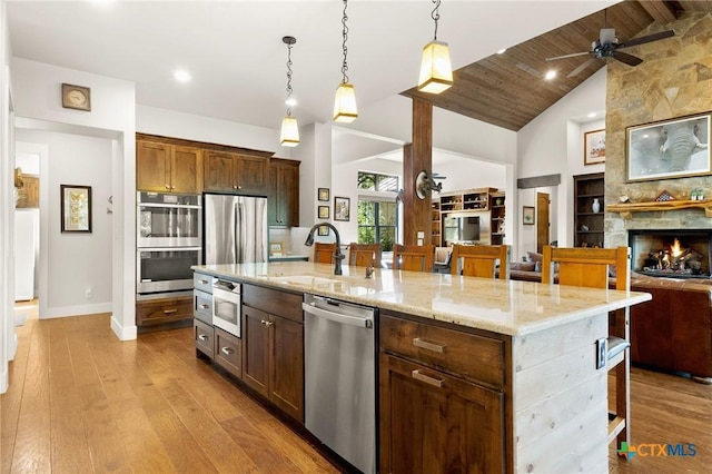 1204 Salt Lick Dr, New Braunfels, TX 78132 - kitchen featuring appliances with stainless steel finishes, open floor plan, high vaulted ceiling, a ceiling fan, and light stone countertops