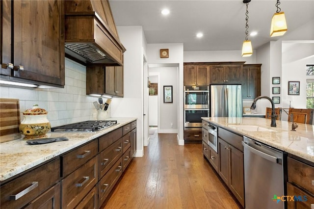 1204 Salt Lick Dr, New Braunfels, TX 78132 - kitchen featuring stainless steel appliances, hanging light fixtures, light stone counters, tasteful backsplash, and dark wood-style flooring