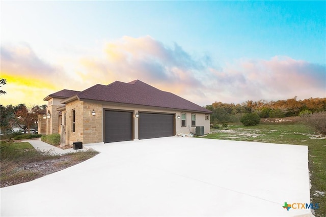 226 Sabella, Spring Branch, TX 78070 - property exterior at dusk with stone siding, a garage, cooling unit, concrete driveway, and a yard