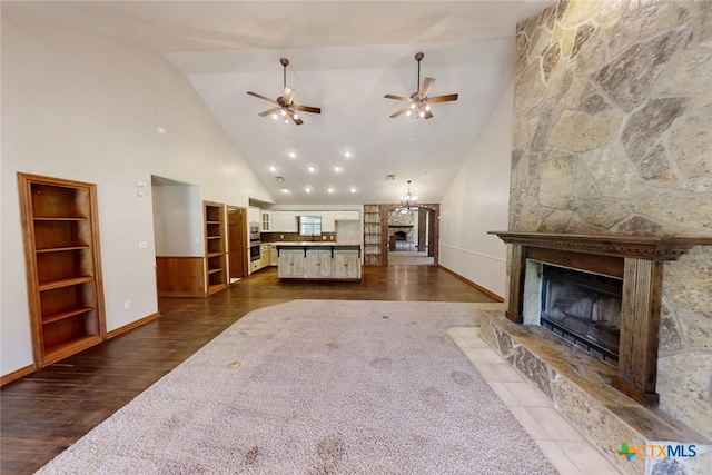 1260 Great Oaks Dr, Salado, TX 76571 - living area featuring a stone fireplace, high vaulted ceiling, a ceiling fan, dark wood-style floors, and built in shelves