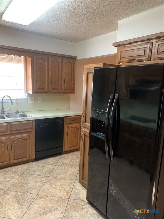 kitchen featuring light tile patterned flooring, a textured ceiling, sink, and black appliances