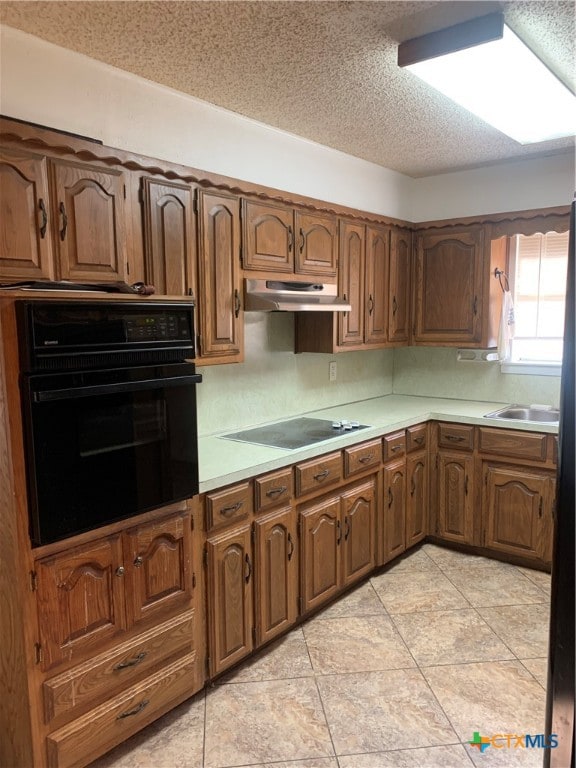 kitchen featuring sink, black oven, electric stovetop, a textured ceiling, and light tile patterned floors