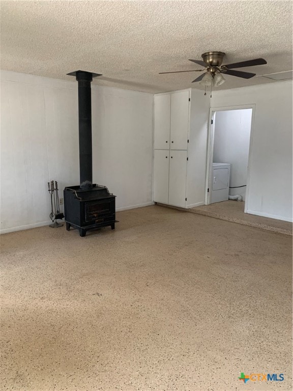 unfurnished living room featuring ceiling fan, a textured ceiling, and a wood stove