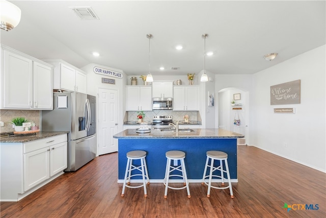 kitchen featuring dark hardwood / wood-style floors, white cabinetry, stainless steel appliances, and an island with sink