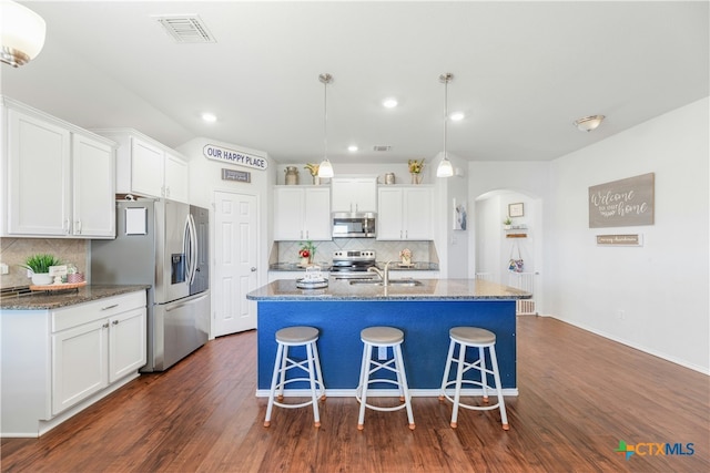 6424 Treiber Dr, Temple, TX 76502 - kitchen with appliances with stainless steel finishes, arched walkways, tasteful backsplash, white cabinets, and a kitchen breakfast bar
