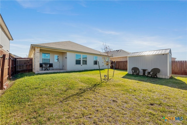 rear view of property featuring a yard, an outbuilding, and a patio