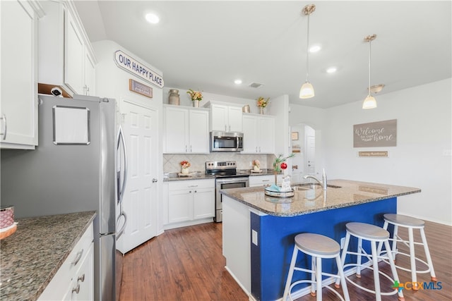 kitchen featuring dark hardwood / wood-style flooring, white cabinetry, hanging light fixtures, and appliances with stainless steel finishes