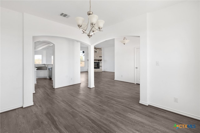 unfurnished dining area with a fireplace, dark hardwood / wood-style floors, and a chandelier