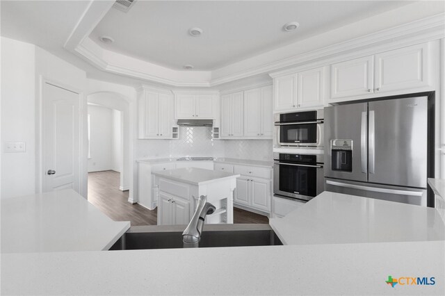 kitchen with dark wood-type flooring, sink, stainless steel fridge with ice dispenser, a kitchen island, and white cabinetry