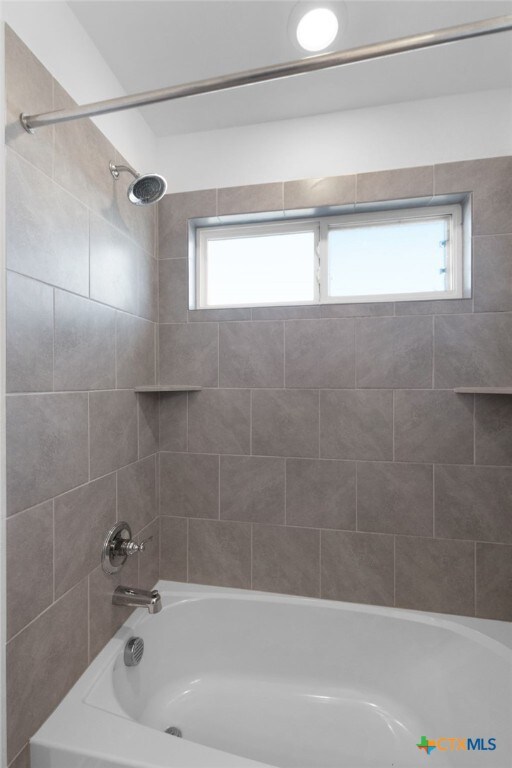 bathroom with a wealth of natural light and tiled shower / bath