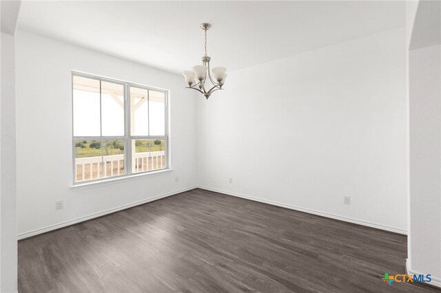 spare room featuring dark hardwood / wood-style flooring and an inviting chandelier