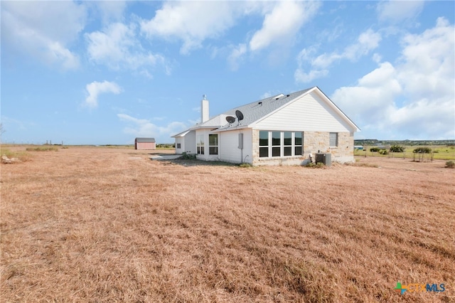 back of property featuring central AC unit and a rural view