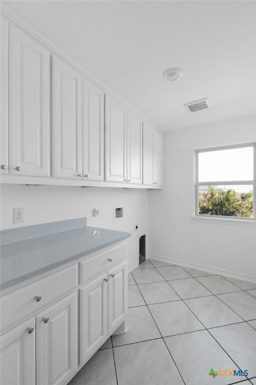 laundry room with hookup for an electric dryer, hookup for a washing machine, cabinets, and light tile patterned floors