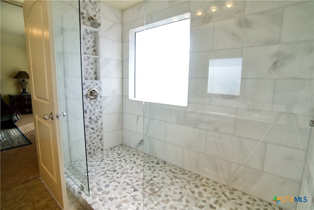 bathroom featuring tile patterned flooring and a tile shower