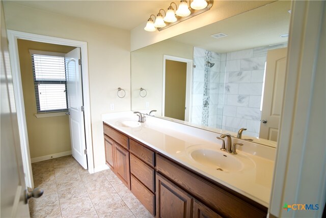 bathroom featuring tile patterned flooring, vanity, and a tile shower