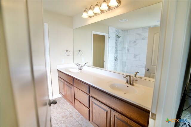 bathroom featuring tile patterned flooring, vanity, and a tile shower