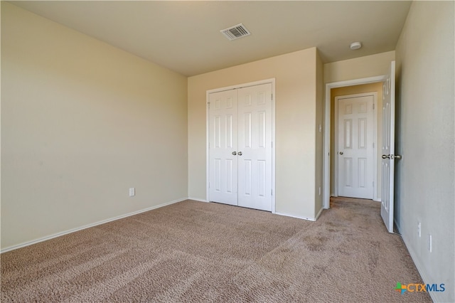 unfurnished bedroom with a closet and light colored carpet