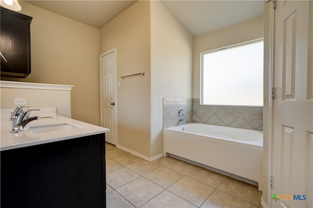 bathroom with a tub to relax in, vanity, and tile patterned floors